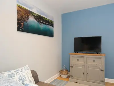 a living room with a flat screen tv on a cabinet at Coastal Haven in Bude