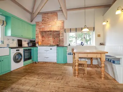a kitchen with green cabinets and a wooden table at The Old Watermill in Bodmin