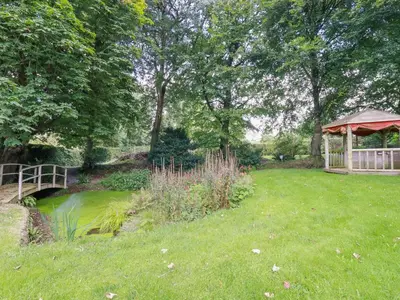 a garden with a bridge and a gazebo at The Old Watermill in Bodmin