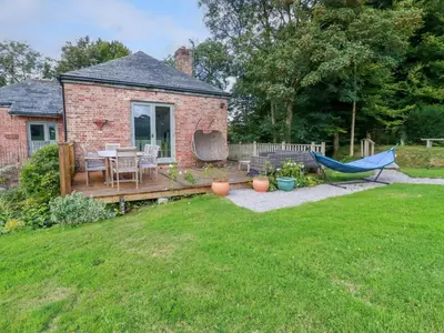 a backyard with a patio with a hammock and a house at The Old Watermill in Bodmin