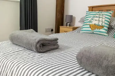 two beds with towels on them in a bedroom at Great Cornish Coastal Retreat in Par