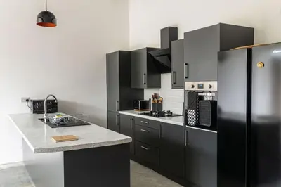 a kitchen with black cabinets and a black refrigerator at Great Cornish Coastal Retreat in Par