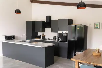 a kitchen with a black refrigerator and a table at Great Cornish Coastal Retreat in Par