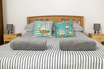 a bed with striped sheets and pillows on it at Great Cornish Coastal Retreat in Par