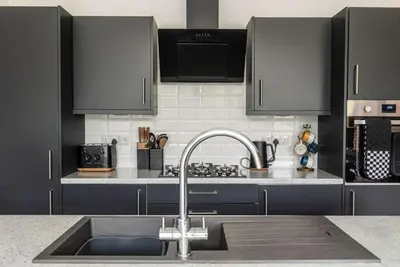 a kitchen with a sink and black cabinets at Great Cornish Coastal Retreat in Par
