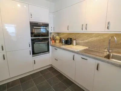 a kitchen with white cabinets and a sink at Mariners Watch in St Ives