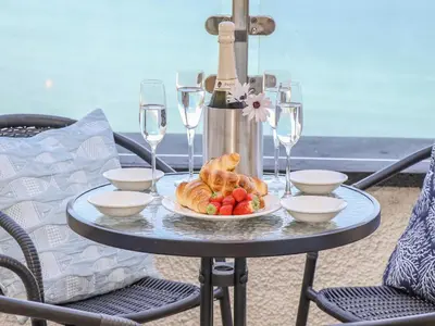 a table with a plate of food and wine glasses at Mariners Watch in St Ives