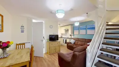 a living room with a couch and a staircase at 06 Strawberry Hill, Tolroy Manor in Hayle