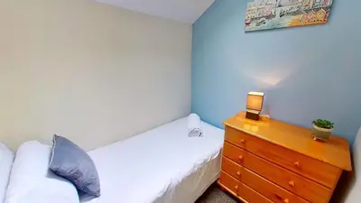 a bedroom with a bed and a dresser with a lamp at 06 Strawberry Hill, Tolroy Manor in Hayle
