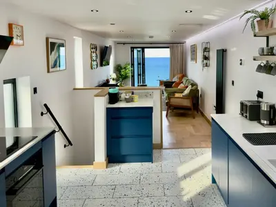 a kitchen with blue cabinets and a living room at Bayvista in St Ives