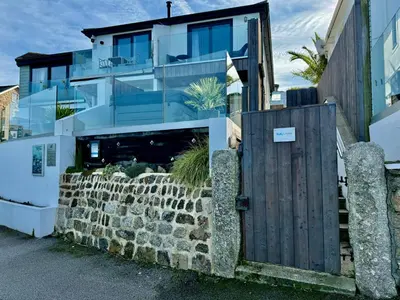 a house with a stone wall and a wooden gate at Bayvista in St Ives