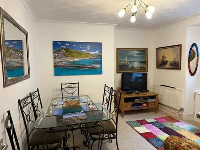a dining room with a glass table and a television at Seaway Beach House Looe Beach in Looe