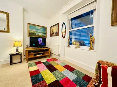 a living room with a television and a colorful rug at Seaway Beach House Looe Beach in Looe