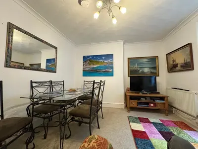 a dining room with a table and a tv at Seaway Beach House Looe Beach in Looe
