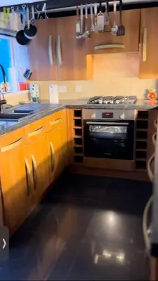 a kitchen with wooden cabinets and a stove top oven at Seaway Beach House Looe Beach in Looe