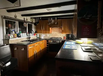 a kitchen with wooden cabinets and a black counter top at Seaway Beach House Looe Beach in Looe