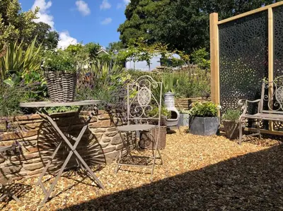 a garden with chairs and a table and a stone wall at The Cuckoo's Nest - A Romantic & Peaceful Hideaway in Kenwyn