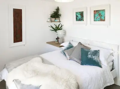 a white bedroom with a white bed with pillows at The Cuckoo's Nest - A Romantic & Peaceful Hideaway in Kenwyn