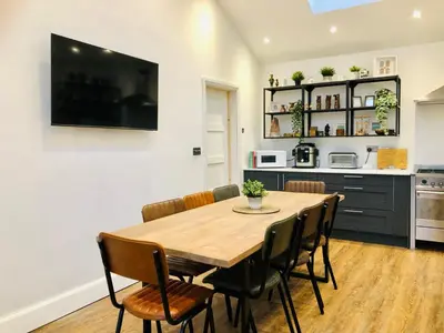 a dining room with a wooden table and chairs at The Cuckoo's Retreat - Luxurious home with private garden & jacuzzi in Kenwyn