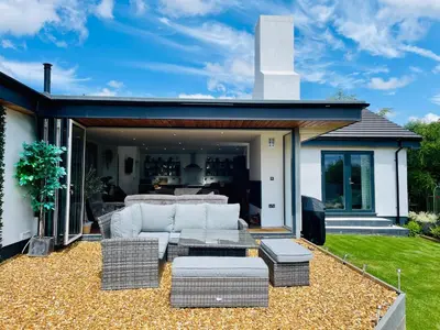 a patio with a couch and chairs and a table at The Cuckoo's Retreat - Luxurious home with private garden & jacuzzi in Kenwyn