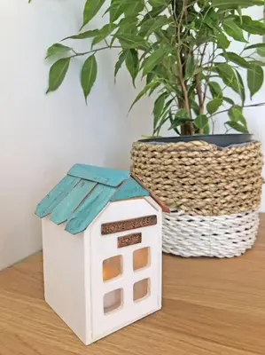 a toy house sitting on a table next to a plant at The Cuckoo's Retreat - Luxurious home with private garden & jacuzzi in Kenwyn