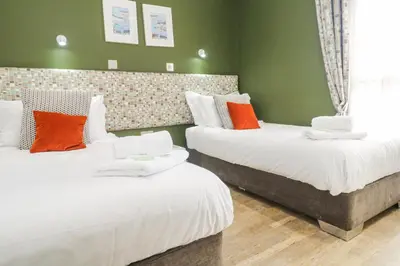 two beds in a room with green walls and orange pillows at Bay View in Redruth
