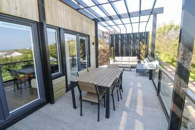 a patio with a wooden table and chairs on a balcony at Bay View in Redruth