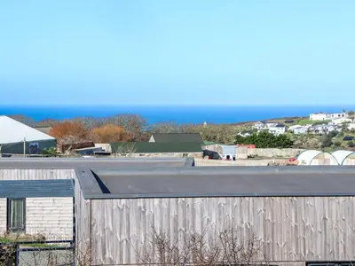 a building with a fence and the ocean in the background at Bay View in Redruth