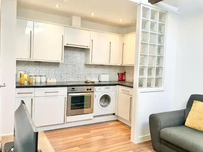 a kitchen with white cabinets and a washer and dryer at Cosy Cornish Hideaway Hayle in Hayle