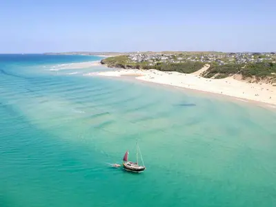 a boat in the water next to a beach at Cosy Cornish Hideaway Hayle in Hayle