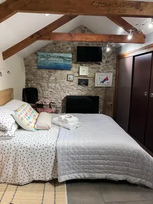 a bedroom with a bed and a stone wall at Anvil The Old Smithey in Saint Erth