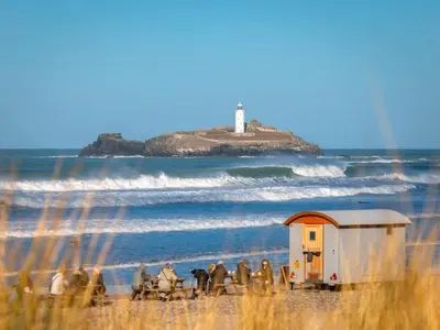 a group of people riding horses on a beach with a lighthouse at Anvil The Old Smithey in Saint Erth
