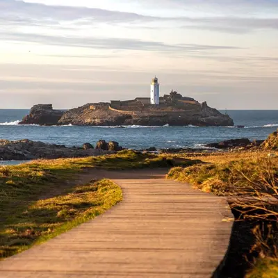 a wooden path leading to a lighthouse on a island at Anvil The Old Smithey in Saint Erth