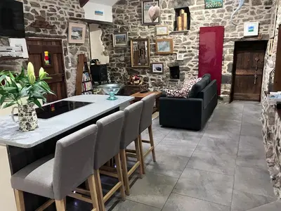 a living room with a stone wall and a table and chairs at Anvil The Old Smithey in Saint Erth