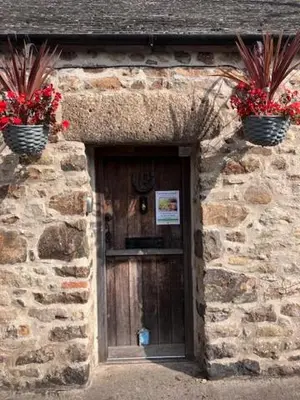 a stone building with two potted plants above a door at Anvil The Old Smithey in Saint Erth