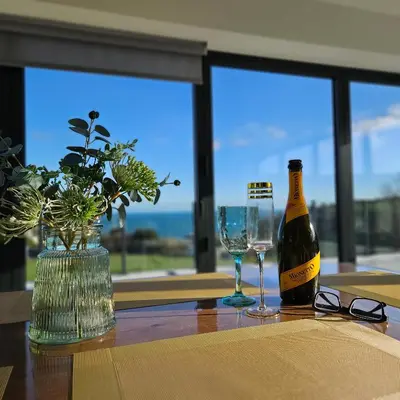 a bottle of wine sitting on a table with glasses at Luxury Seaview, Modern, 6 beds in Mevagissey