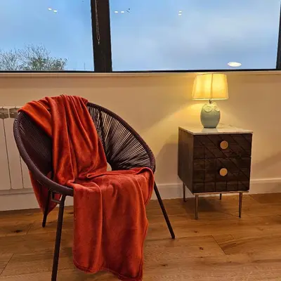 a chair with a blanket on it next to a table at Luxury Seaview, Modern, 6 beds in Mevagissey