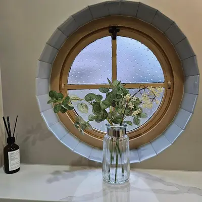 a vase with flowers sitting on a table in front of a window at Luxury Seaview, Modern, 6 beds in Mevagissey
