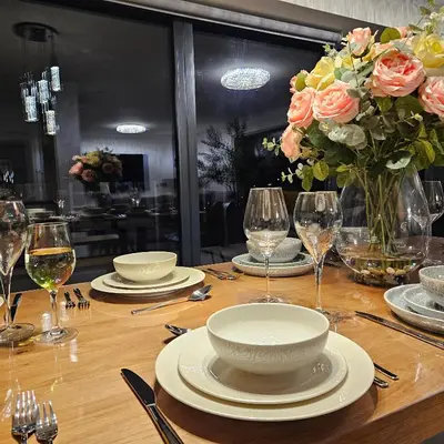 a table with plates and glasses and a vase of flowers at Luxury Seaview, Modern, 6 beds in Mevagissey