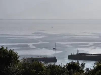 a large body of water with a boat and a lighthouse at Luxury Seaview, Modern, 6 beds in Mevagissey