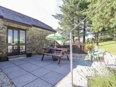 a patio with a picnic table and an umbrella at The Hayloft in Liskeard