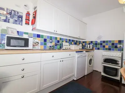 a kitchen with white cabinets and a microwave at The Hayloft in Liskeard