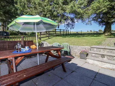 a wooden picnic table with an umbrella on top of it at The Hayloft in Liskeard