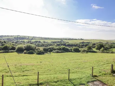 a field of green grass with a fence at The Hayloft in Liskeard