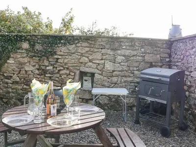 a grill and a picnic table with glasses and a stove at The Hayloft in Liskeard