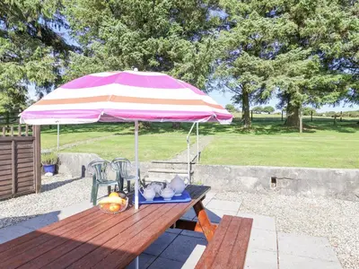 a picnic table with a pink and white umbrella at The Dairy in Liskeard