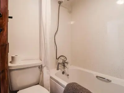a white bathroom with a toilet and a bath tub at The Byre in Liskeard