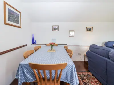 a dining room with a table and a blue couch at The Byre in Liskeard