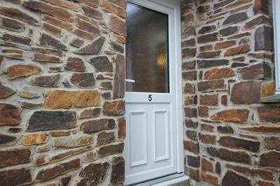 a white door in a brick wall with the number six at The BarnsPigallie in Redruth
