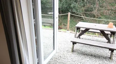 a picnic table with a hat sitting on it next to a window at The BarnsPigallie in Redruth